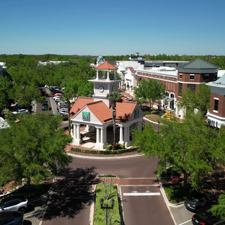 Aerial view of Winter Garden Village at Fowler Groves shopping center, with its clock-tower pavilion, brick storefronts and tree-lined streets, Winter Garden FL